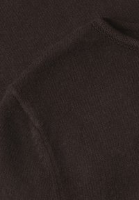 Gros plan d'un tissu tricoté doux de couleur brun foncé montrant une texture détaillée et des plis subtils.
