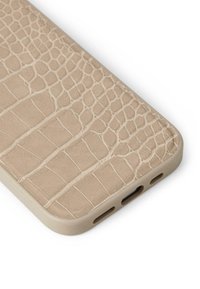 Beige telefonveske med krokodillemønster og en strukturert overflate. Runde kanter og åpninger for porter er synlige.