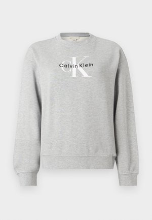 Ανοιχτό γκρι φούτερ με στρογγυλή λαιμόκοψη και μακριά μανίκια, με το λογότυπο "Calvin Klein" σε μαύρο και άσπρο στο στήθος.