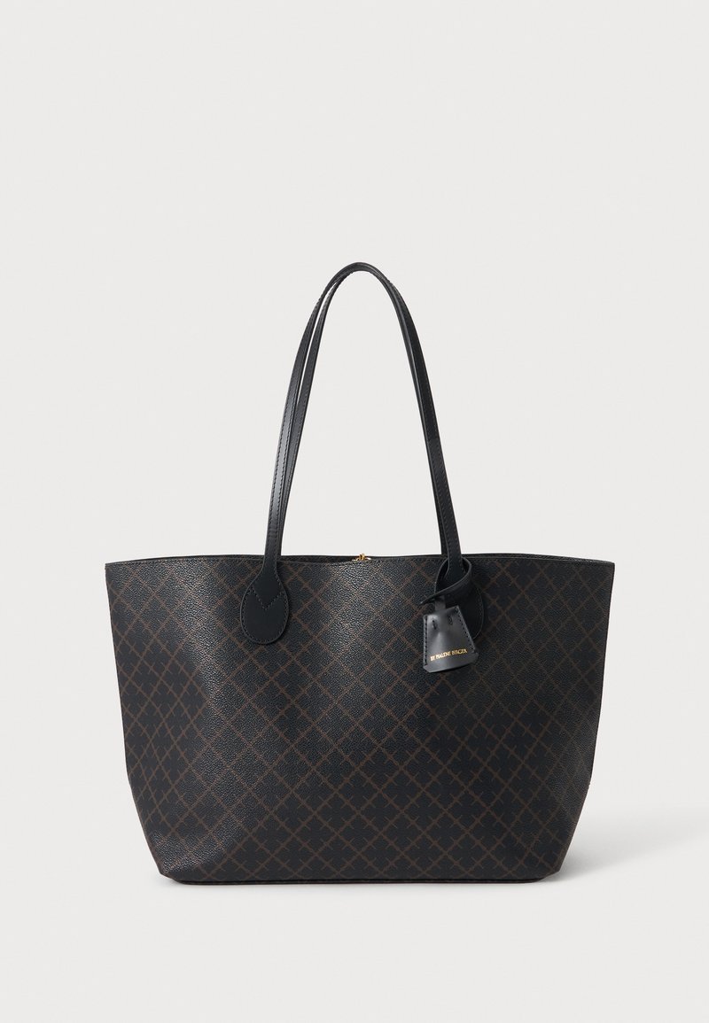 Grand sac cabas marron foncé avec anses en cuir noir et une petite étiquette noire attachée avec une écriture dorée sur fond blanc.