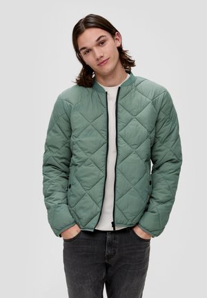 Pikowana, jasnozielona kurtka z okrągłym kołnierzem, zapięciem na zamek i czarnymi akcentami, charakteryzująca się teksturowanym wykończeniem oraz dwiema kieszeniami bocznymi.