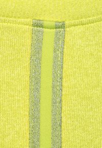 Stickad tyg i starkt gult med en central texturerad remsa i reflekterande silvertråd. Slät yta med ribbad finish.