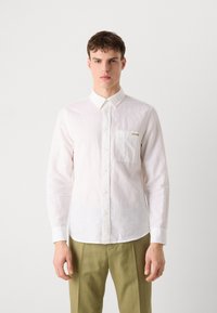 Camicia bianca a maniche lunghe in tessuto leggero, con colletto a punta, taschino frontale e un sottile logo distintivo. Vestibilità sartoriale.
