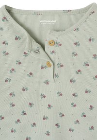 Light green ribbed fabric with small red and green floral print, two wooden buttons, and a round neckline with a partial button placket.