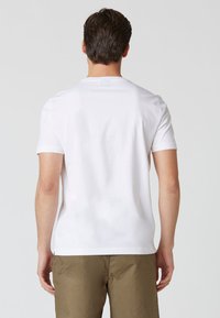 T-shirt bianca a maniche corte in cotone, con scollatura a girocollo, una texture liscia e un design della schiena semplice.