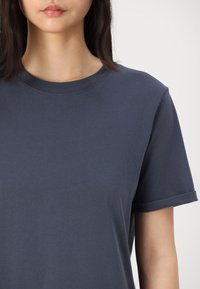 Navy blue cotton t-shirt with a crew neck and short sleeves. Smooth texture, rolled sleeve cuffs, and simple design without patterns.
