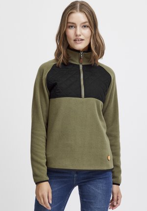 Fleece pullover i olivengrøn med en sort quiltet sektion på brystet. Har en halv-zip krave og et lille orange logo i sømmet.