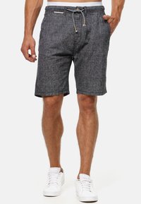 Sort og grå mønstrede shorts lavet af letv�ægtsstof, med en justerbar snøre i livet og opfoldede sømme. Båret med hvide sneakers.