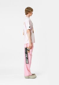 Camiseta rosa de gran tamaño con estampado de animales, combinada con pantalones rosas con un acento texturizado y zapatos casuales de tipo slip-on.