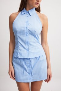 Light blue halter top with vertical white stripes and button closure, featuring a fitted design and a matching short skirt.
