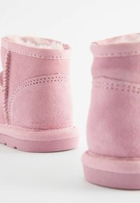 Rosa mockaskinnsanklar med en mjuk, texturerad yta. Har en mysig, pälsfodrad insida och en robust, räfflad gummisul.