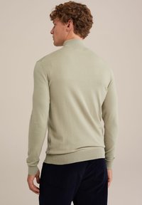 Šviesiai žalia megzta džemperis su aukštu apykakle, gipiūro užbaigimais ir kraštu, pasižymintis lygiu paviršiumi ir prigludusia išvaizda.