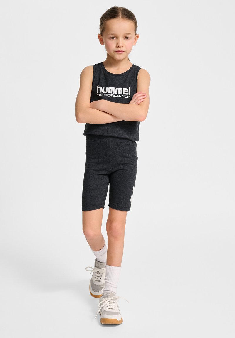 Svart atletisk tvådelad outfit bestående av en ärmlös topp med vit logotyp och åtsittande shorts. Bärs med grå och krämfärgade sneakers.