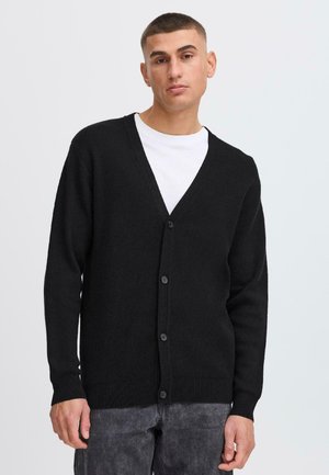 Svart cardigan laget av teksturert stoff, med V-hals, lange ermer og seks knapper foran.