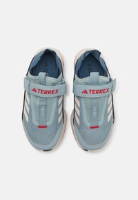 Blue athletic shoes with mesh upper and white accents, featuring a hook-and-loop strap, textured sole, and contrasting red lettering.