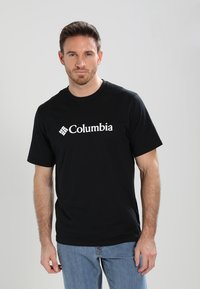 Zwarte katoenen T-shirt met een wit "Columbia" logo aan de voorkant, ronde halslijn en korte mouwen. Draag het met lichtblauwe jeans.