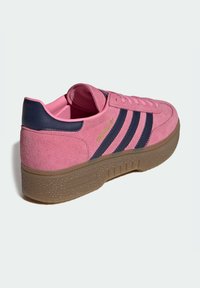 Rosa mockasneaker med marinblå ränder och detaljer, rillad gummisula, rundad form och guldfärgad logotypdetalj på sidan.