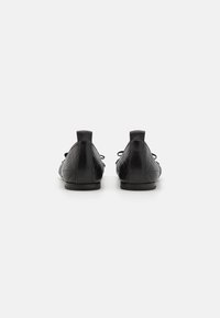 Chaussures en cuir noir avec un design matelassé, bout rond et semelle plate. Équipées de lacets et d'une petite languette à l'arrière pour un enfilage facile.