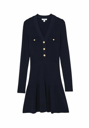 Marineblauwe gebreide jurk met lange mouwen, V-hals, twee borstzakken en vijf gouden knopen. Heeft een uitlopende zoom en geribbelde textuur.