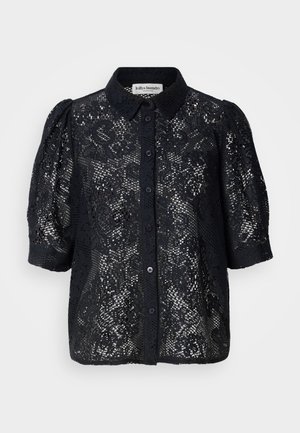 Blouse en dentelle noire avec manches courtes bouffantes, devant boutonné et motif floral complexe. Tissu en dentelle texturé avec une finition semi-transparente.