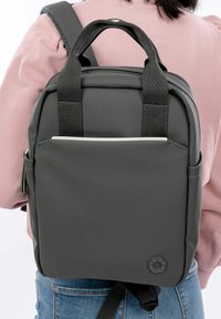 Harmaa reppu, joka on valmistettu teksturoidusta materiaalista. Siinä on kaksi yläkädensijaa, säädettävät olkahihnat ja minimalistinen etutasku.