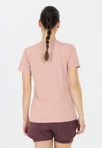 Kortärmad rosa t-shirt av mjukt tyg, kombinerad med mörk maroon shorts. Slät textur, avslappnad passform och minimal design.