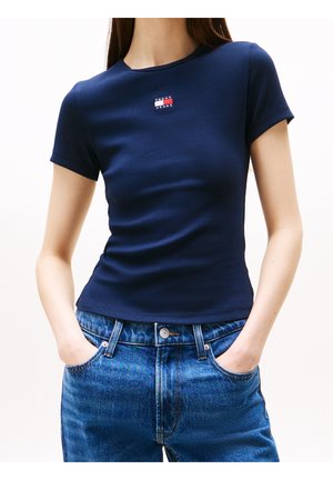 Marineblauwe geribbelde T-shirt met korte mouwen en een ronde halslijn. Heeft een klein, multikleurig "Tommy Jeans" logo op de borst.