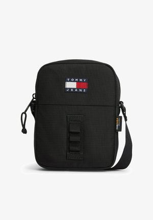 Kompaktowa czarna torba na ramię Tommy Jeans z przednią naszywką z logo, metką wykonanej z tkaniny Cordura, zamknięciem na zamek oraz regulowanym paskiem na ramię.