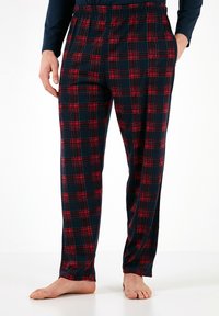 Pantalones de pijama de cuadros en azul marino con acentos en rojo y blanco, presentan una cinturilla elástica y bolsillos laterales, confeccionados en un tejido suave.