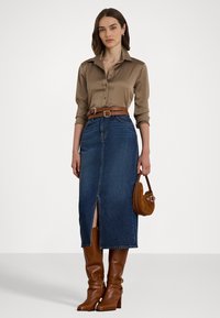 Brūna satīna krekls ar pogām, zilas denim svārki ar priekšējo šķirumu, brūns ādas josta un potīšu zābaki, kā arī neliela brūna rokassoma.