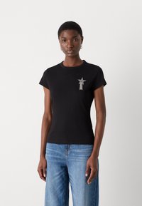 Black cotton t-shirt with a round neckline, short sleeves, and a star-shaped silver embellishment on the left chest.