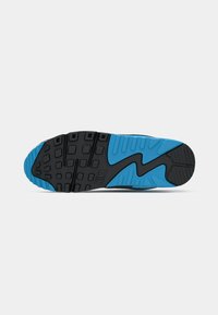 Black and blue sneaker outsole with textured, rubber material. Features a zigzag pattern and square traction nubs for grip.