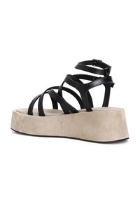Sandales noires à lanières avec plusieurs fines lanières, une semelle plateforme beige et une finition texturée. Bride de cheville ajustable pour un bon ajustement.