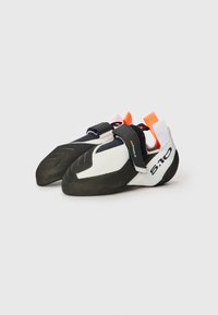 Sapatos de escalada com um cabedal branco e sola de borracha preta. Possui um fecho de Velcro, bico arredondado e alças de puxar laranja.