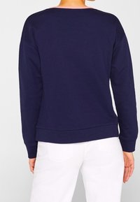 Sudadera azul marino con cuello redondo, mangas largas y puños de canalé. Presenta una textura suave y elegante, además de un corte holgado.