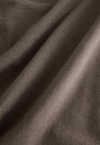 Țesătură de bumbac maro cu o textură netedă, având pliuri subtile și un luciu delicat, evidențiind draparea sa flexibilă și suprafața uniformă.