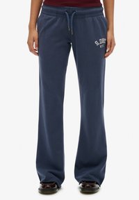 Granatowe dresy wykonane z miękkiego materiału, z elastycznym pasem na sznurku oraz białym logo "S.DRY N.Y.C" na lewym biodrze.