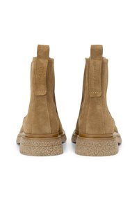 Bottines en daim marron avec une semelle en caoutchouc texturée. Dotées d'une languette pour un enfilage facile, avec des détails de couture sur les côtés.