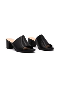 Mule in pelle nera aperta sulla punta con tacco a blocco di altezza media. Texture liscia e design minimalista, caratterizzata da un logo goffrato discreto sul tacco.