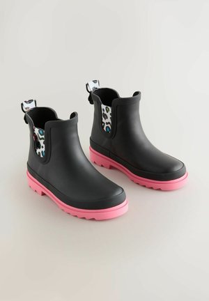 Svarta vattentäta chelsea-boots med rosa sulor, strukturerat gummimaterial och ett mönstrat innerfoder i olika färger.