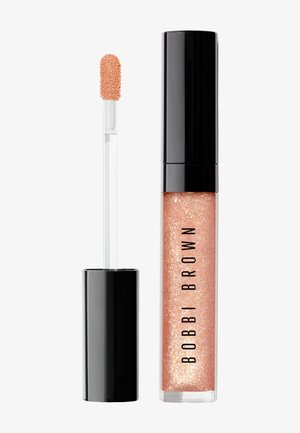 Glossy peach-toned lip gloss with shimmer in clear tube, black cap, and applicator wand beside it, labeled "Bobbi Brown."