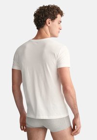 Weißes Baumwoll-T-Shirt mit kurzen Ärmeln, Rundhalsausschnitt und lockerer Passform, kombiniert mit grauem Boxershorts. Einfaches, klassisches Design.