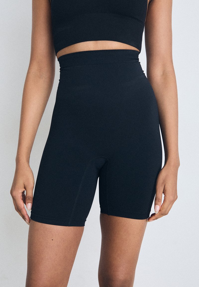 Høyt midjebånd svart sykkelshorts laget av elastisk stoff, med en tettsittende design og sømløs konstruksjon, egnet for aktiv bruk.