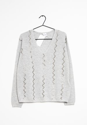 Pull gris clair à manches longues avec col en V et motifs verticaux en zigzag en fil argenté, suspendu sur un cintre noir avec étiquettes attachées.