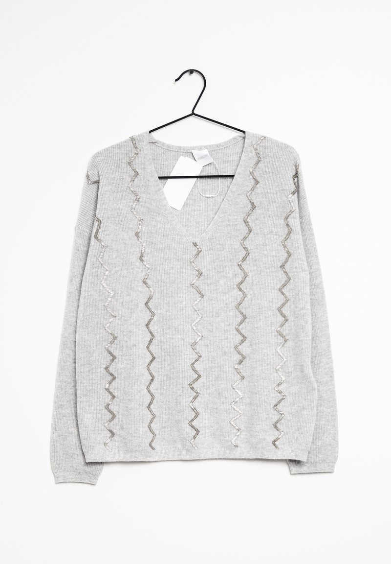 Pull gris clair à manches longues avec col en V et motifs verticaux en zigzag en fil argenté, suspendu sur un cintre noir avec étiquettes attachées.