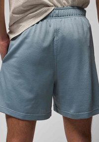 Lyseblå træningsshorts lavet af tekstureret mesh-stof. De har en elastisk talje og en afslappet pasform med lommer.