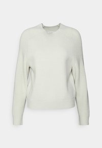 Krämfärgad långärmad stickad tröja med rundad halsringning och strukturerade muddar, nederkant och detaljer på axlarna, uppvisad mot en vit bakgrund.