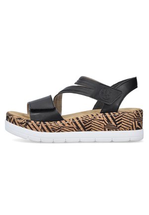 Černé kožené klínové sandály mají křížové pásky a nastavitelné přezky. Platforma má korkovou texturu s geometrickým vzorem a je umístěna na bílé podrážce.