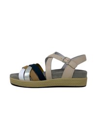 Sandali multicolori con cinturini beige, caratterizzati da un design a strisce orizzontali in bianco, argento, blu navy e marrone. Suola intrecciata con presa.
