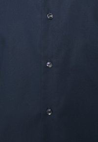 Navyblauwe knoopsluiting shirt gemaakt van gladde katoen; heeft zwarte knopen langs de knoopsluiting, met een schoon, eenvoudig ontwerp.